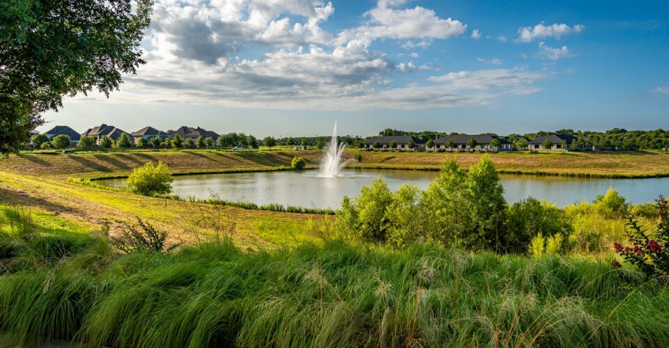 Auburn Hills trail with nice flowers, green grass and a beautiful water fountain in the middle of the pond.