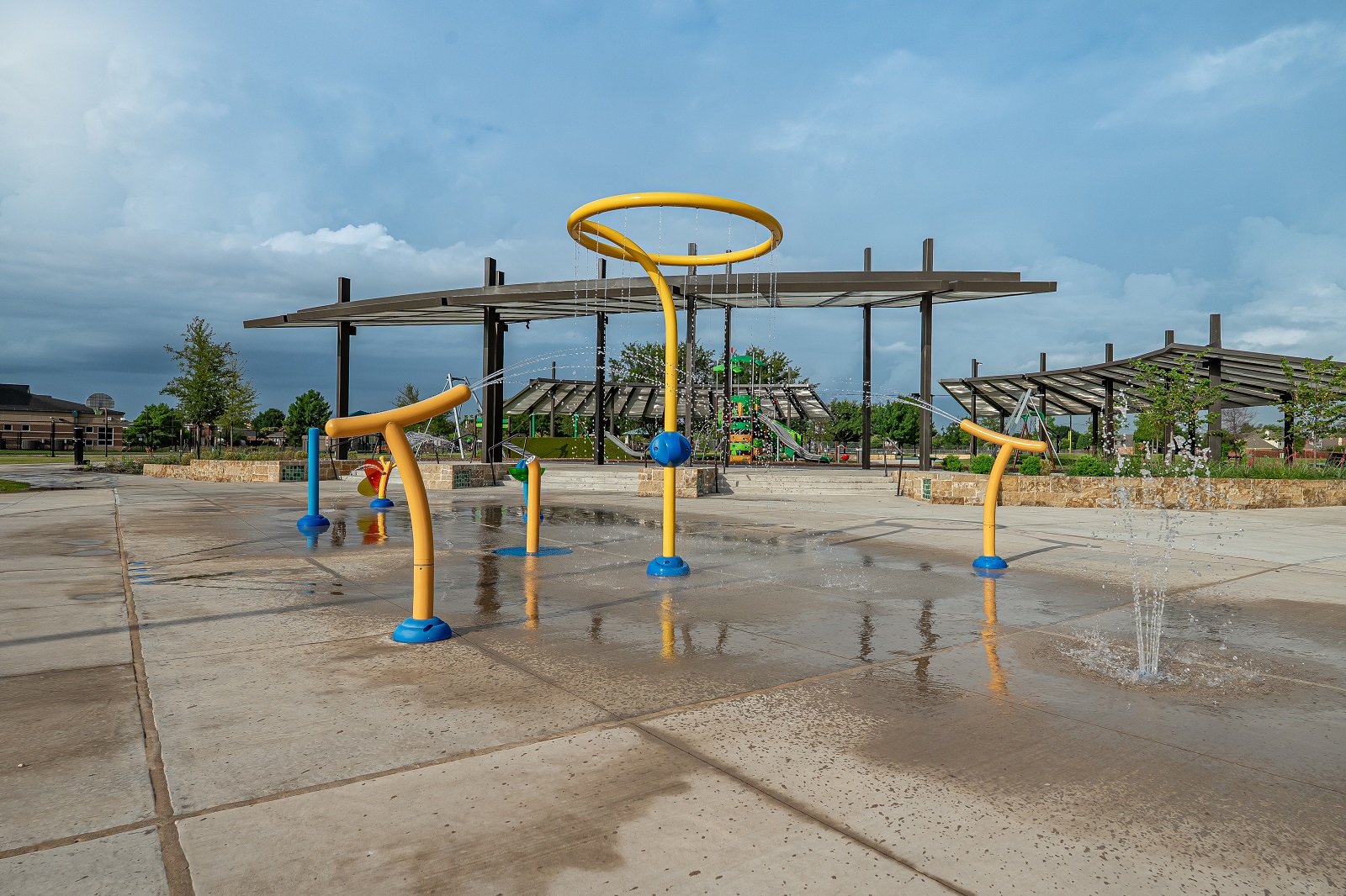 E.A. Randles park splash pad features tall, medium, and short sprayers, yellow and blue.