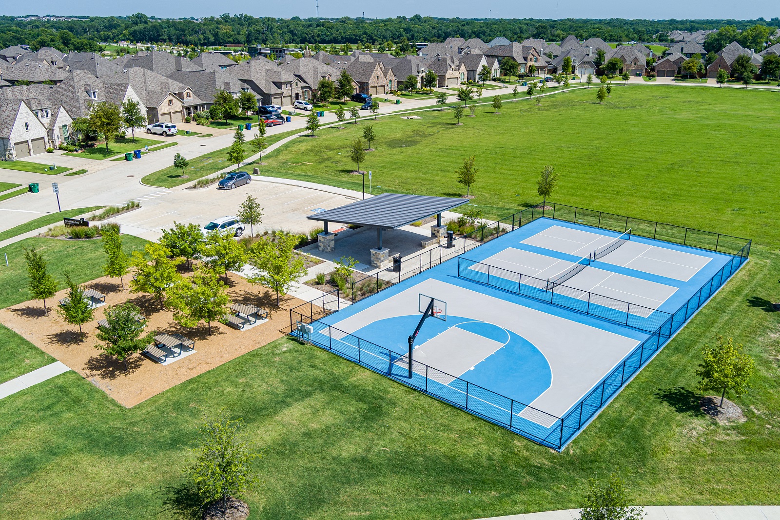 Forest Ridge park aerial of the park with green grass, walking path, playground, multi-sport courts, and pavilion