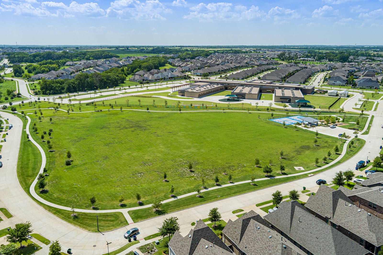 Forest Ridge park aerial of the park with green grass, walking path, playground, multi-sport courts.