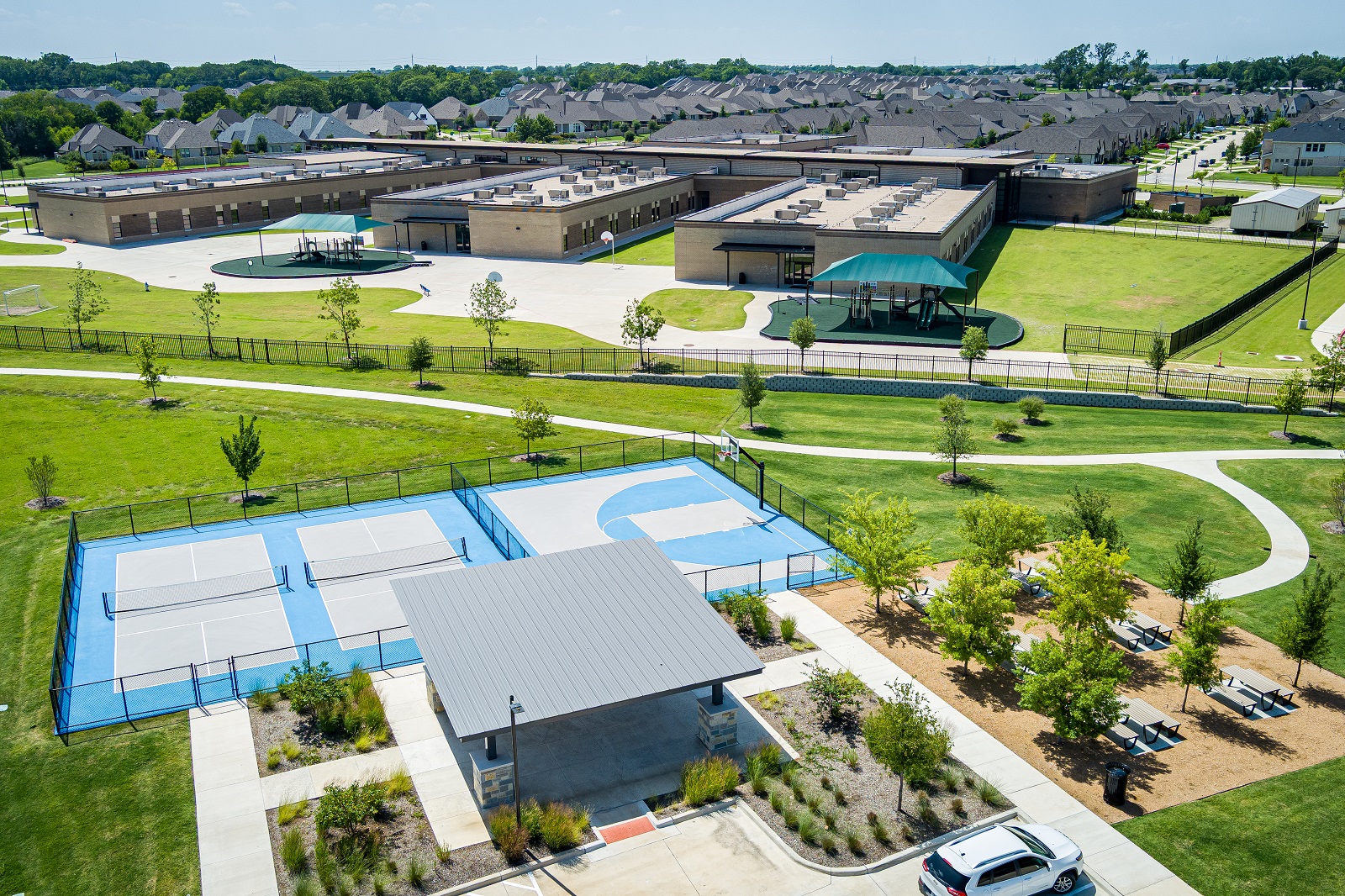 Forest Ridge park aerial of the park with green grass, walking path, playground, multi-sport courts.