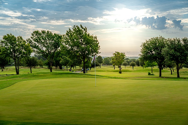 Oak hollow golf course with one of the greens, a flag in the hole and a beautiful sunset shot
