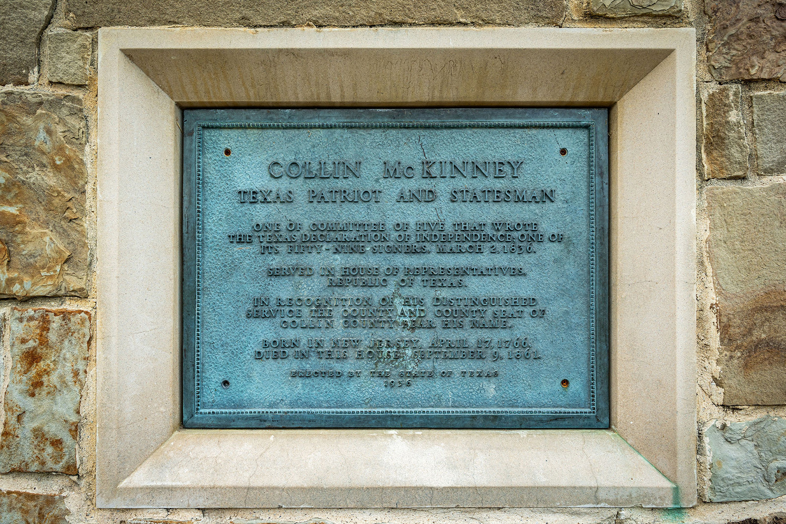 A metal plaque set in stone honors Collin McKinney, Texas patriot and statesman, with details about his life and contributions.